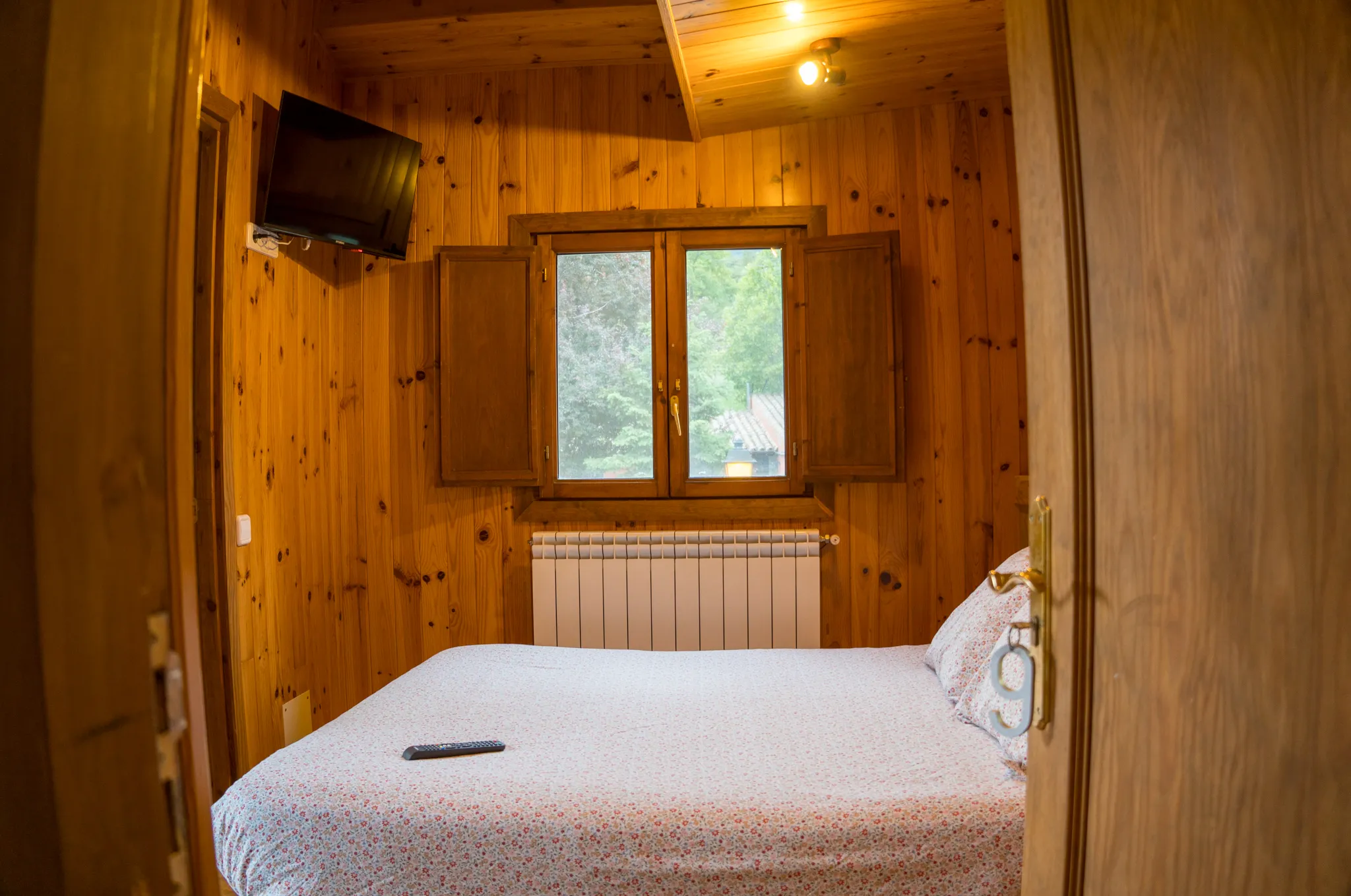 Habitació de la casa rural amb paret de pedra, fusta i vistes a la muntanya