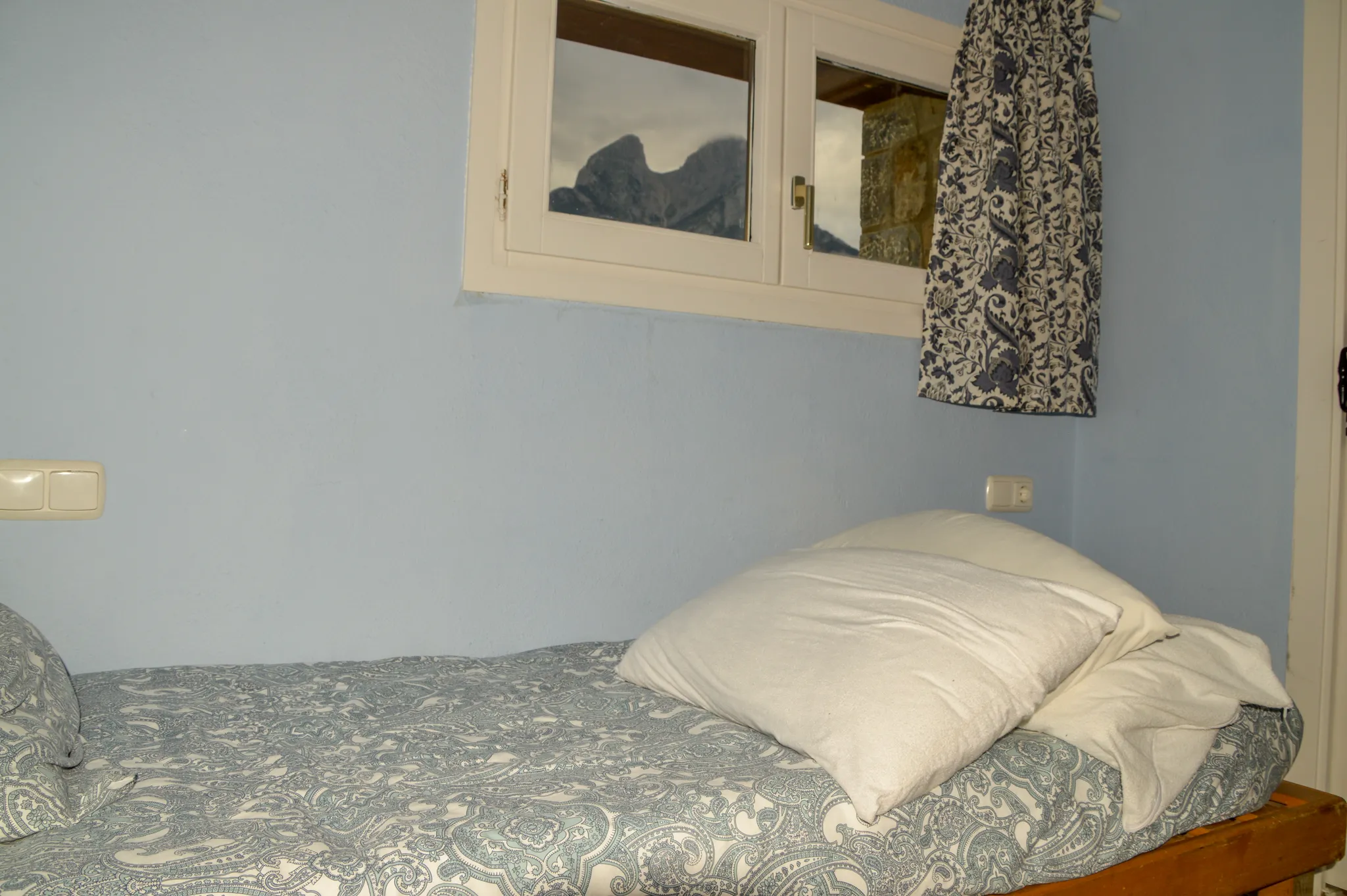 Habitació de la casa rural amb paret de pedra, fusta i vistes a la muntanya