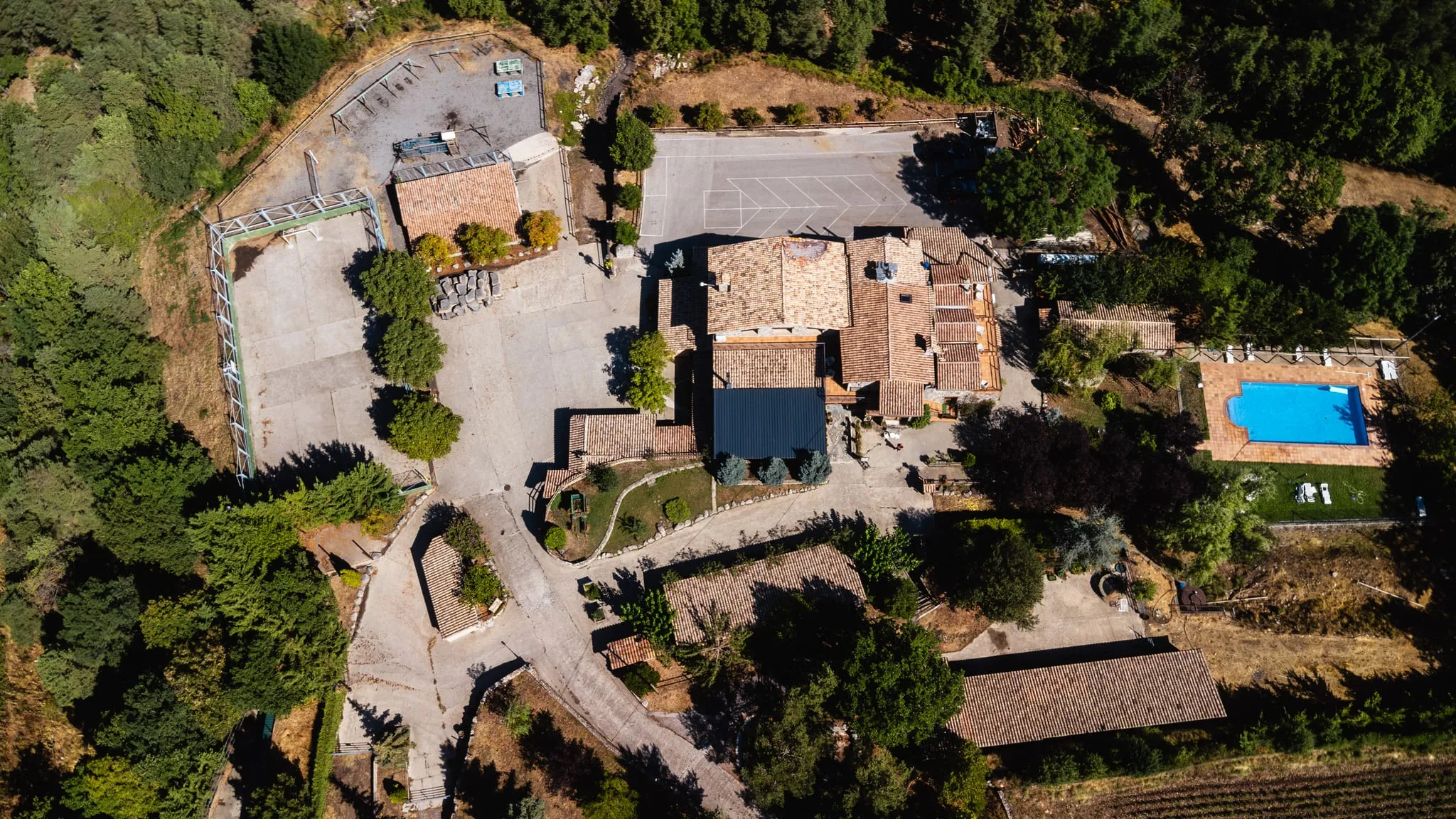 Vista zenital de la casa: les cases de pedra, els patis, els jardins i la piscina enmig del bosc