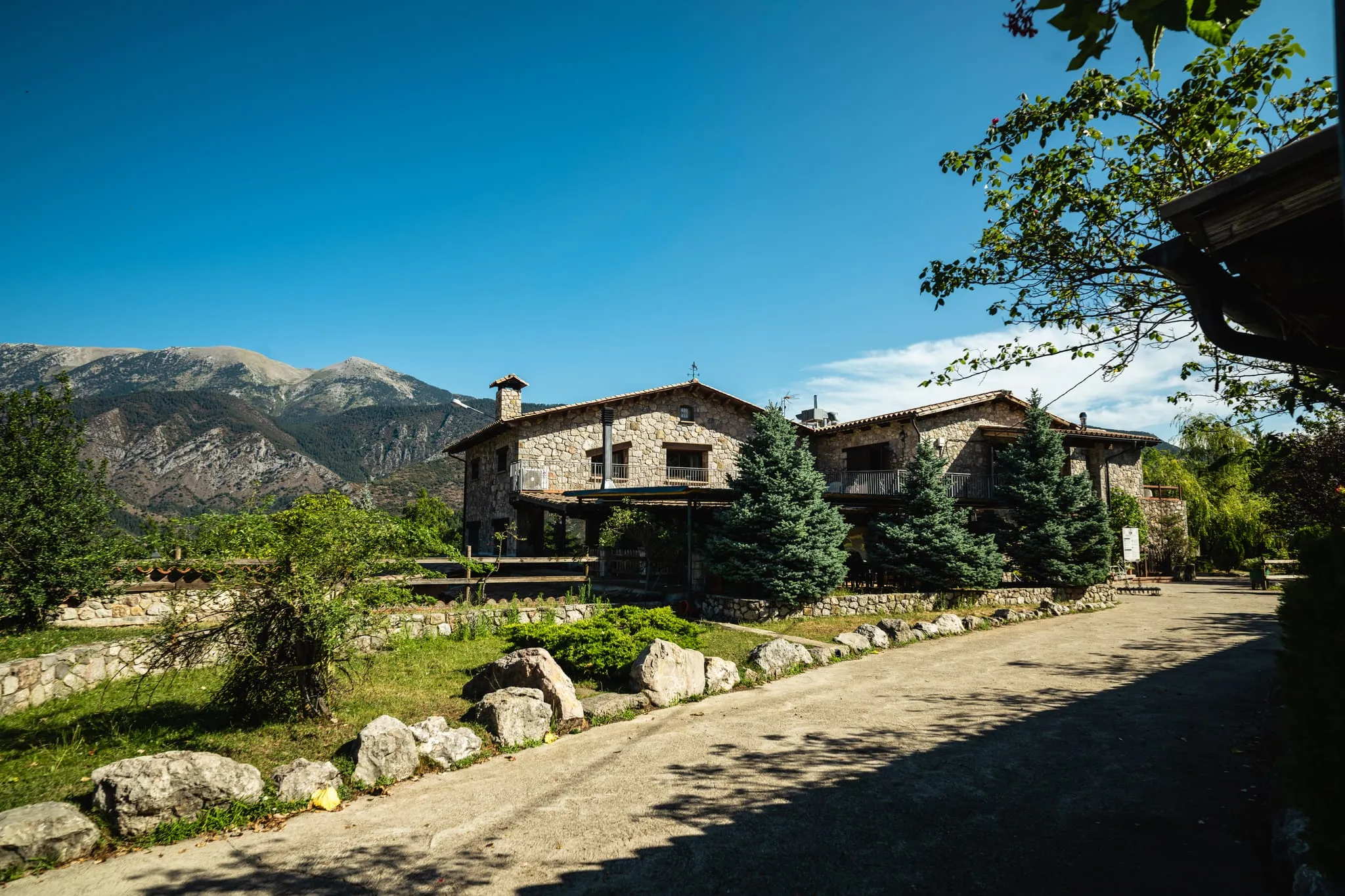 Les cases de pedra entre avets i jardins, amb les muntanyes al fons