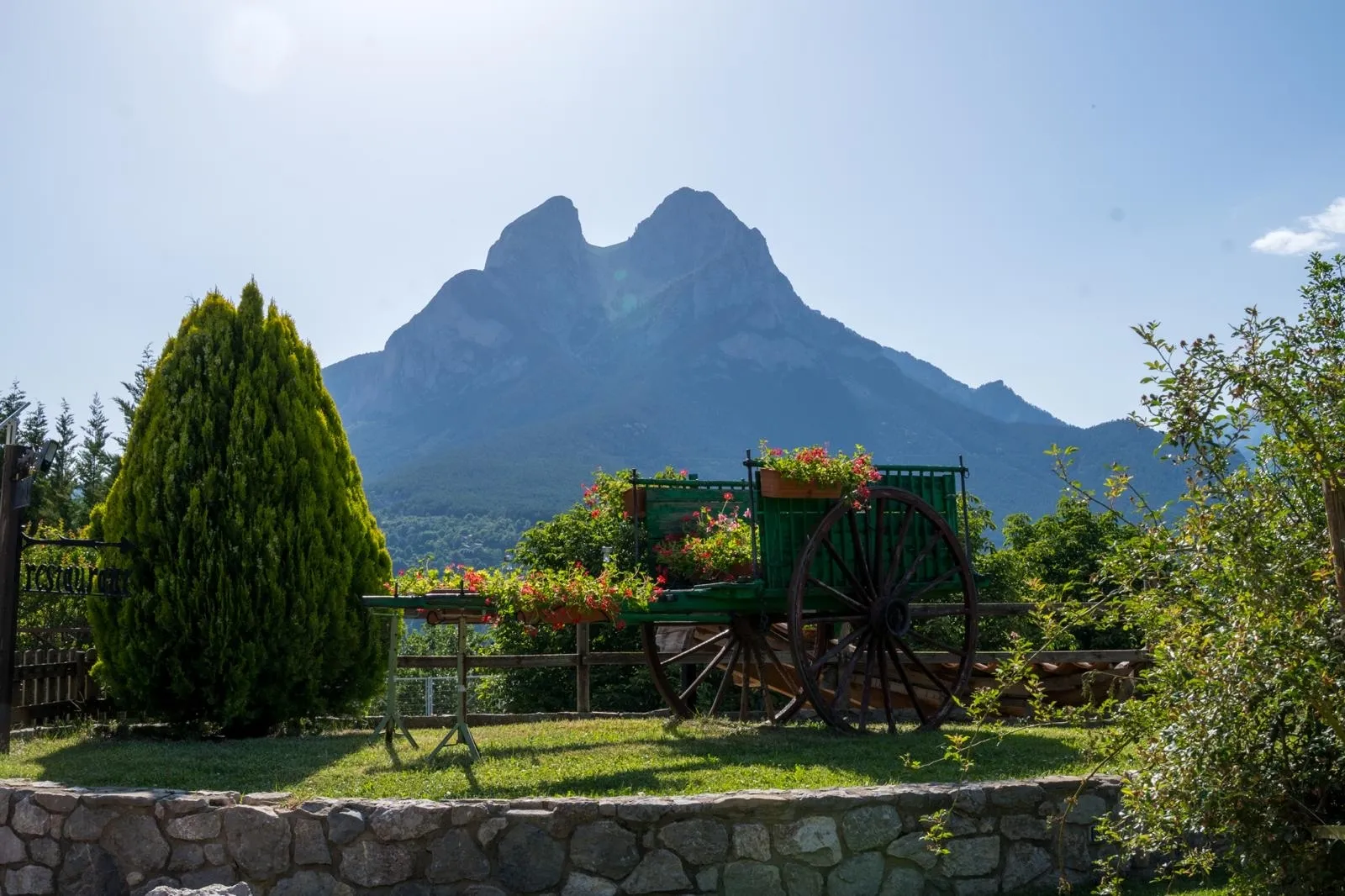 El massís del Pedraforca vist des dels jardins de la casa, amb un carro de fusta guarnit amb flors