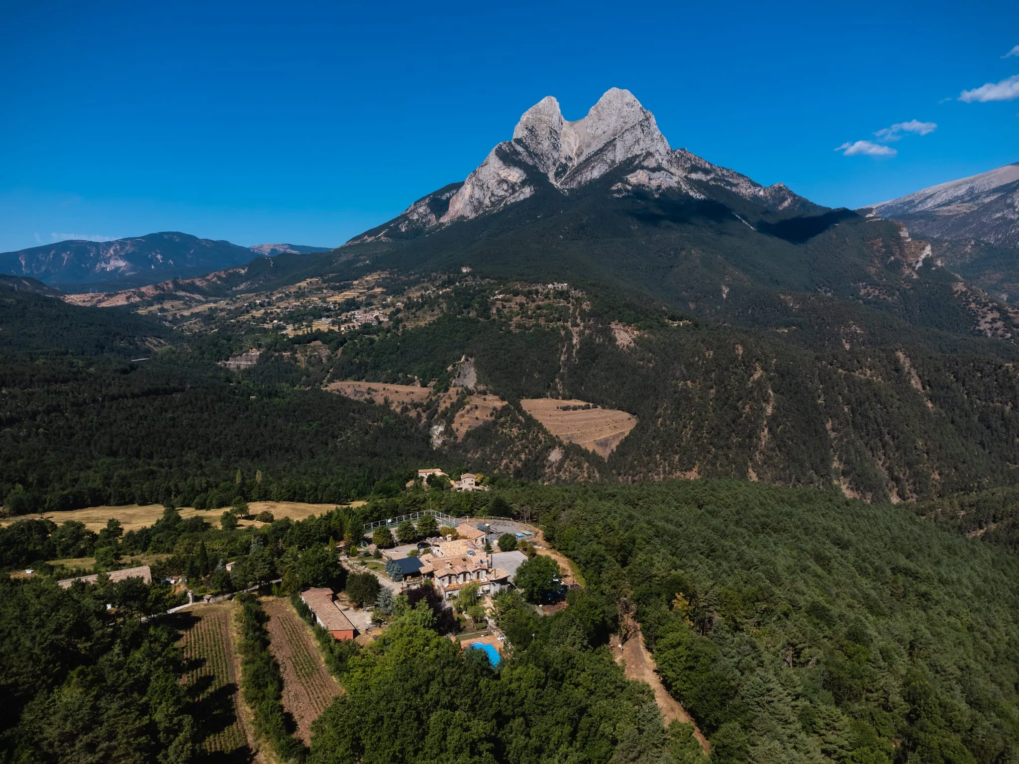 Vista aèria de la casa enmig del bosc, als peus del massís del Pedraforca